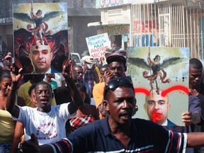 Demonstrators carry defaced portraits of Haitian Prime Minister Laurent Lamothe during an anti-government protest in Port-au-Prince December 5, 2014. REUTERS/Marie Arago