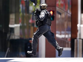 A police officer runs across Martin Place near Lindt cafe, where hostages are being held, in central Sydney December 15, 2014. Hostages were being held inside the central Sydney cafe where a black flag with white Arabic writing could be seen in the window, local television showed on Monday, raising fears of an attack linked to Islamic militants.       
REUTERS/David Gray