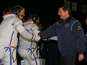 Russian Federal Space Agency Roscosmos head Oleg Ostapenko (R)  shake hands with U.S. astronaut Steven Swanson, a crew member of a mission to the International Space Station (ISS)  as he goes to board Soyuz-FG rocket with the Soyuz TMA-12M spacecraft at the Russian-leased Baikonur cosmodrome in Kazakhstan, early on March 26, 2014.   (AFP PHOTO/POOL/DMITRY LOVETSKY)