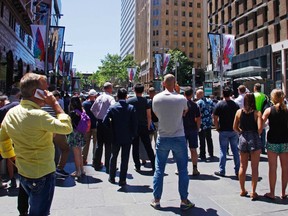 People standing behind a police cordon look towards Lindt cafe in Martin Place, where hostages are being held, in central Sydney December 15, 2014. Dozens of hostages were trapped inside the central Sydney cafe on Monday, with local television showing some being forced to hold up a black flag with white Arabic writing in the window, raising fears of an attack linked to Islamic militants.  REUTERS/David Gray