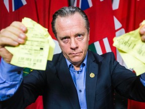 Former attorney general of Ontario Michael Bryant poses with copies of parking tickets at the end of a press conference at Queen's Park in Toronto on Monday, December 15, 2014. (Ernest Doroszuk/Toronto Sun)