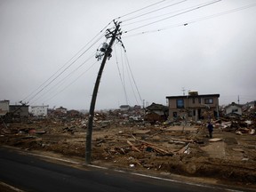 A man walks near a damaged power pole at an area that was devastated by the March 11 earthquake and tsunami, in Watari, Miyagi prefecture, in this April 22, 2011 file photo. (REUTERS)