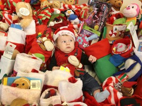 Three-month-old Justice Scanlon isn't quite sure of all the strange creatures around as the youngster sits in the middle of more than 160 stockings filled with toys for children in two programs at the Kingston Community Health Centres in Kingston. (Michael Lea/The Whig-Standard)