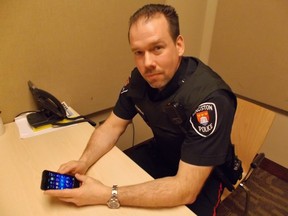 Kingston Police Const. Steven Koopma​n, with his phone at Kingston Police headquarters. (Emma Brown/For The Whig-Standard)
