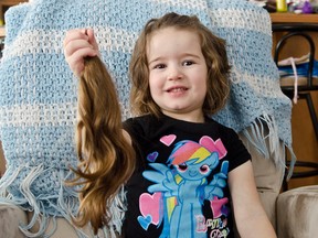 Three-year-old Danika Touchette poses at her home holding the hair she had cut and is donating to Angel Hair for Kids.