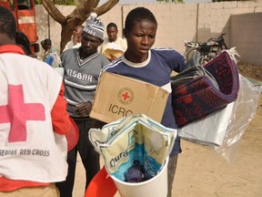 A man carries relief materials distributed by the Red Cross in Kano at a relief camp for people fleeing the Boko Haram violence, in Dawaki, a local government area in Kano, December 16, 2014.  (REUTERS/Stringer)