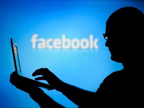 A man is silhouetted against a video screen with a Facebook logo as he poses with a laptop in this photo illustration taken in the central Bosnian town of Zenica in this August 14, 2013 file photo. (REUTERS/Dado Ruvic/Files)