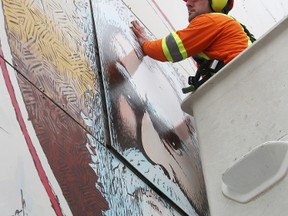 Arbourist Cory King affixes a replacement panel for the Sir Joseph Hobson mural in downtown Sarnia. Sign artist Dave Beatty repainted the piece after the original went missing last winter. TYLER KULA/ THE OBSERVER/ QMI AGENCY