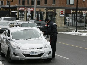 Const. Kyle Steele of the Ottawa police Escort Unit hands a driver a ticket for using a cellphone while driving last December. Steele was one of several officers taking part in a three-day distracted driving blitz which saw more than 250 tickets handed out. DOUG HEMPSTEAD/Ottawa Sun files
