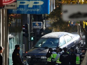 Policemen stand guard as the car driven into the headquarters of Spain's ruling People's Party (PP)  is towed away in Madrid on December 19, 2014. (REUTERS/Juan Medina)