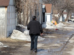 A man walks down a back lane on Dufferin Avenue in Winnipeg, Man. Sunday April 20, 2014 after two males were found seriously injured Saturday night. One male later died.