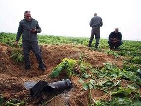 Israeli security forces stand next to the remains of a rocket that was fired from the Gaza Strip towards Israel on Friday, on the Israeli side of the border December 19, 2014. The military said it was the third rocket fired from Gaza since the end of the July-August conflict. No Palestinian group claimed responsibility for the attack.  REUTERS/Ilan Assayag