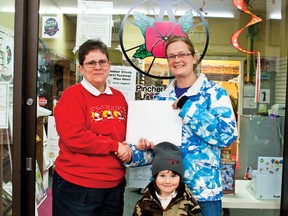 (L to R) Sharon Roberts, chamber of commerce president, presents Brandi Hutchison and her son Phillip with $1250 worth of gift certificates to local businesses for winning the Countdown to Christmas passport contest.