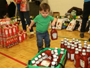JOHN LAPPA/THE SUDBURY STAR
Medric Raymond, 2, collects ketchup bottles for distribution at the Club Richelieu Les Patriotes food drive at Ecole St-Joseph. About 60 club members and volunteers gathered in the gymnasium to sort and distribute Christmas food baskets for 124 families in Greater Sudbury.