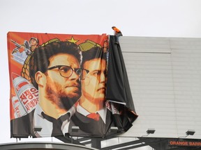 Workers remove a poster-banner for "The Interview" from a billboard in Hollywood, California, December 18, 2014 a day after Sony announced was cancelling the movie's Christmas release due to a terrorist threat.   AFP PHOTO / MICHAEL THURSTON