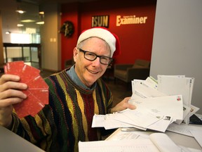 Graham Hicks holds up gift cards as he opens letters with donations for Adopt-A-Teen at the Sun Offices in Edmonton, on Tuesday Dec. 23, 2014. FILE PHOTO