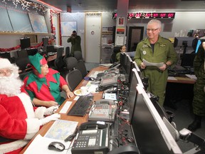 Chris Procaylo/QMI Agency
Santa and one of his elves get their pre-flight operational briefing from Lieutenant-Colonel Darrell Marleau, Combat Operations Division Chief (left),  before their flight through Canadian Airspace.