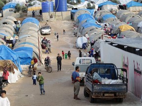 People who were internally displaced from Hama and Idlib, walk in a refugee camp beside the Syrian-Turkish border in Qtma town, Idlib countryside December 18, 2014. (REUTERS/Khalil Ashawi)
