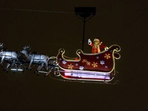 TOPSHOTSA man wearing a Santa Claus costume waves from his sleigh as he carried over the Champs Elysees avenue in Paris on December 23, 2014 in Paris. AFP PHOTO / KENZO TRIBOUILLARD