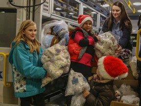 Children of York Region emergency services load up ambulances full of teddy bears donated by Ganz Inc. to give to kids in hospital emergency rooms and children's wards across York Region. From left, Taylor, 12, Daniella, 7, and Marcus, 4, hand toys to student paramedic Samantha on Wednesday December 24, 2014. (Dave Thomas/Toronto Sun)