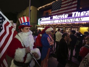 Matt Ornstein, dressed in a Santa Claus costume, holds an American flag as fans line up at the Silent Movie Theatre for a midnight screening of "The Interview" in Los Angeles, Dec. 24, 2014. REUTERS/Jonathan Alcorn