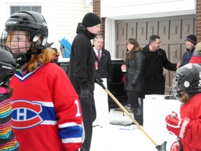 Children play on the Vincents' front yard hockey rink on Monaco Crescent Tuesday, Dec. 23, 2014 while in the background Cornwall Mayor Leslie O'Shaughnessy is seen explaining the reasons why the rink boards must be taken down to conform with a property bylaw. 
GREG PEERENBOOM/CORNWALL STANDARD-FREEHOLDER/QMI AGENCY
