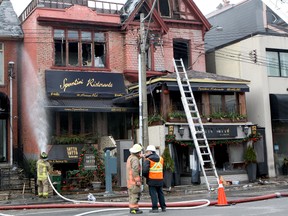 A Toronto Fire Services district chief talks to an investigator from the Ontario Fire Marshal's office as firefighters continued to douse hot spots at Spuntini Ristorante and Sotto Sotto on Boxing Day 2014. (CHRIS DOUCETTE/TORONTO SUN)