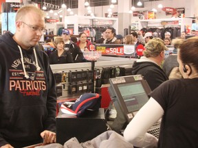 Jon Hyde waits for his purchases to be rung through at Sport Chek in Lambton Mall Friday, as a lineup of other shoppers look on. Retailers in Sarnia say Boxing Day is their busiest day of the year. TYLER KULA/ THE OBSERVER/ QMI AGENCY