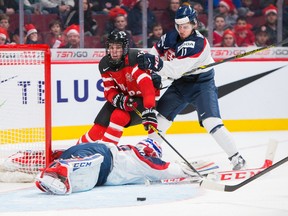 Canada's Connor McDavid tries to reach a loose puck over Slovakian goaltender David Okolicany while being checked by Matus Holenda during the 2015 World Junior Championship on December 26, 2014 at the Bell Centre in Montreal. (JOHANY JUTRAS /QMI Agency)