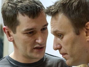Russian anti-Kremlin opposition leader Alexei Navalny (R) listens to his brother and co-defendant Oleg as they attend the verdict announcement of their fraud trial at a court in Moscow on December 30, 2014.