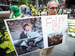 A man holds up a sign in memory of U.S. journalist James Foley during a protest against the Assad regime in Syria in Times Square in New York August 22, 2014. Foley, who was abducted in Syria in late 2012, was beheaded by a masked member of the Islamic State group in an act filmed in a video released on August 19 that also threatened a second American journalist, Steven Sotloff.  REUTERS/Carlo Allegri