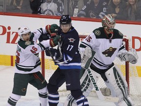 Minnesota Wild defenceman Jared Spurgeon (left) tangles Winnipeg Jets left winger Adam Lowry  in front of Wild goalie Darcy Kuemper during NHL hockey Dec. 29, 2014.