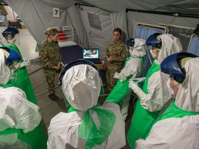 Wearing personal protective equipment, members of the Canadian Armed Forces medical team review video of the next stage of training during Operation Sirona pre-deployment training with their British counterparts at the Army Medical Services Training Centre in Strensall, UK on Dec. 11. The Canadians are now relieving the British at a treatment centre in Sierra Leone.