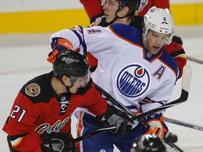 Taylor Hall tangles with a couple of Flames players during last Saturday's meeting between the two teams in Calgary. (Al Charest, QMI Agency)