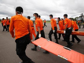 Indonesian Search and Rescue crews walk out to meet a helicopter carrying the bodies of two AirAsia passengers recovered from the sea, at Iskandar airport in Pangkalan Bun, Central Kalimantan, December 31, 2014. (REUTERS/Darren Whiteside)