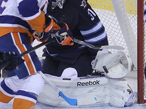 Winnipeg Jets goaltender Ondrej Pavelec looks for a loose puck with New York Islanders forward Josh Bailey parked in front during NHL action at MTS Centre in Winnipeg, Man., on Wed., Dec. 31, 2014. (Kevin King/Winnipeg Sun/QMI Agency)