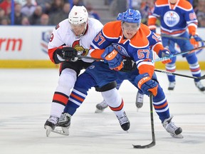 Edmonton Oilers forward David Perron reaches for the puck as he’s held back by Ottawa Senators winger Milan Michalek during NHL play at Rexall Place in Edmonton. (Steve Alkok/USA TODAY Sports)