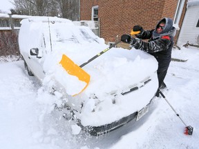 Rob Blundell of Owen Sound uses his snow shovel to push about 8 inches of snow off his neighbour's truck in Owen Sound, Ont. on Thursday, January 1, 2015.  James Masters/QMI Agency