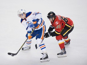 Edmonton Oilers left winger David Perron, left, skates the puck away from Calgary Flames centre Markus Granlund on Wednesday December 31, 2014 at the Scotiabank Saddledome in Calgary, Alta. Carys Richards/Special to the Calgary Sun/QMI Agency