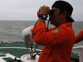 An Indonesian rescue team member uses binoculars to look for suspicious objects, from the deck of SAR ship Purworejo, during a search operation for passengers onboard AirAsia flight QZ8501 in the Java Sea, Indonesia January 2, 2015.   REUTERS/Beawiharta