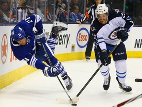 David Clarkson of the Toronto Maple Leafs gets knocked off the puck by Zach Redmond of the Winnipeg Jets during NHL action at the Air Canada Centre in Toronto on  April 5, 2014. (Dave Abel/Toronto Sun)