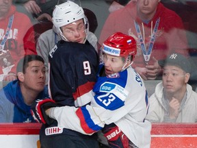 Jack Eichel of the U.S. (left) is wrapped up by Russia’s Alexander Sharov in a quarterfinal match at the 2015 IIHF world junior championship in Montreal on Friday. (PIERRE-PAUL POULIN/QMI Agency)