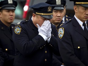 Police officers listen to a closed circuit simulcast of slain New York Police Department officer Wenjian Liu's funeral in the Brooklyn borough of New York January 4, 2015. REUTERS/Carlo Allegri
