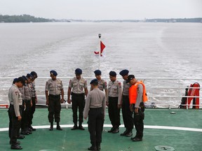 Indonesian policemen involved in the search operation for passengers onboard AirAsia Flight QZ8501 pray onboard the deck of the Search and Rescue (SAR) ship KN Purworejo in the Java Sea January 3, 2015. Bad weather forced divers trying to identify sunken wreckage from the crashed AirAsia passenger jet to abort their mission on Sunday and Indonesian officials said they had not yet picked up any signals from the lost plane's "black box".    REUTERS/Beawiharta
