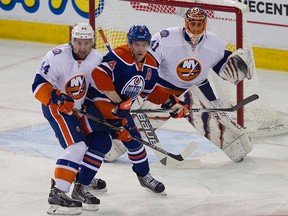 The Edmonton Oilers' Taylor Hall (4) battles the New York Islanders' Calvin de Haan (44) in front of Jaroslav Halak (41) during first period NHL action at Rexall Place, in Edmonton Alta., on Sunday Jan. 4, 2015. David Bloom/Edmonton Sun/QMI Agency