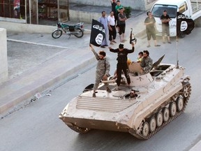 Militant Islamist fighters hold the flag of Islamic State (IS) while taking part in a military parade along the streets of northern Raqqa province in this June 30, 2014 file photo. (REUTERS/Stringer)
