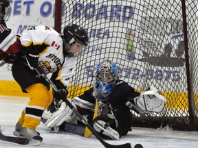 Brendan Sipple (1) of the Stratford Warriors keeps his eye on the loose puck in front of his net while Mitchell Novice AE forward Jaxen Hartwig races for it during action last Friday, Jan. 2. Stratford won this game 3-0. ANDY BADER/MITCHELL ADVOCATE