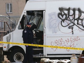 A Toronto police officer stands next to a truck that contained the dead body of a man in the Davenport and Lansdowne area of Toronto on Monday January 5, 2015. (Michael Peake/Toronto Sun)