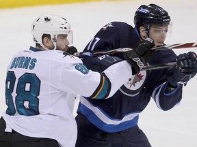 San Jose Sharks defenceman Brent Burns (left) checks Winnipeg Jets left winger Adam Lowry during NHL hockey in Winnipeg, Man. Monday, Jan. 5, 2015.