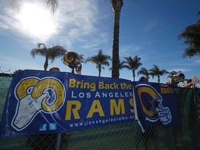NFL fans Tom Bateman (L-R), 43, Skye Sverdlin, 36, Daniel Balma, 36, and Joe Ramirez, 54, show their support for the St. Louis Rams NFL team to come to Los Angeles at a news conference to unveil plans for development at the site of the former Hollywood Park Race Track in Inglewood, Los Angeles, California, January 5, 2015. (REUTERS)